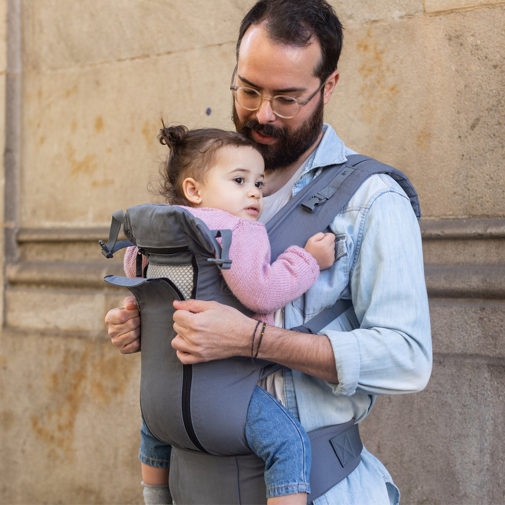 Front facing baby in a Beco 8 Baby Carrier unzipping the mesh for ventilation