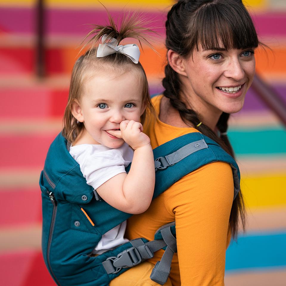 Beco 8 carrier in teal with a baby in back carry position